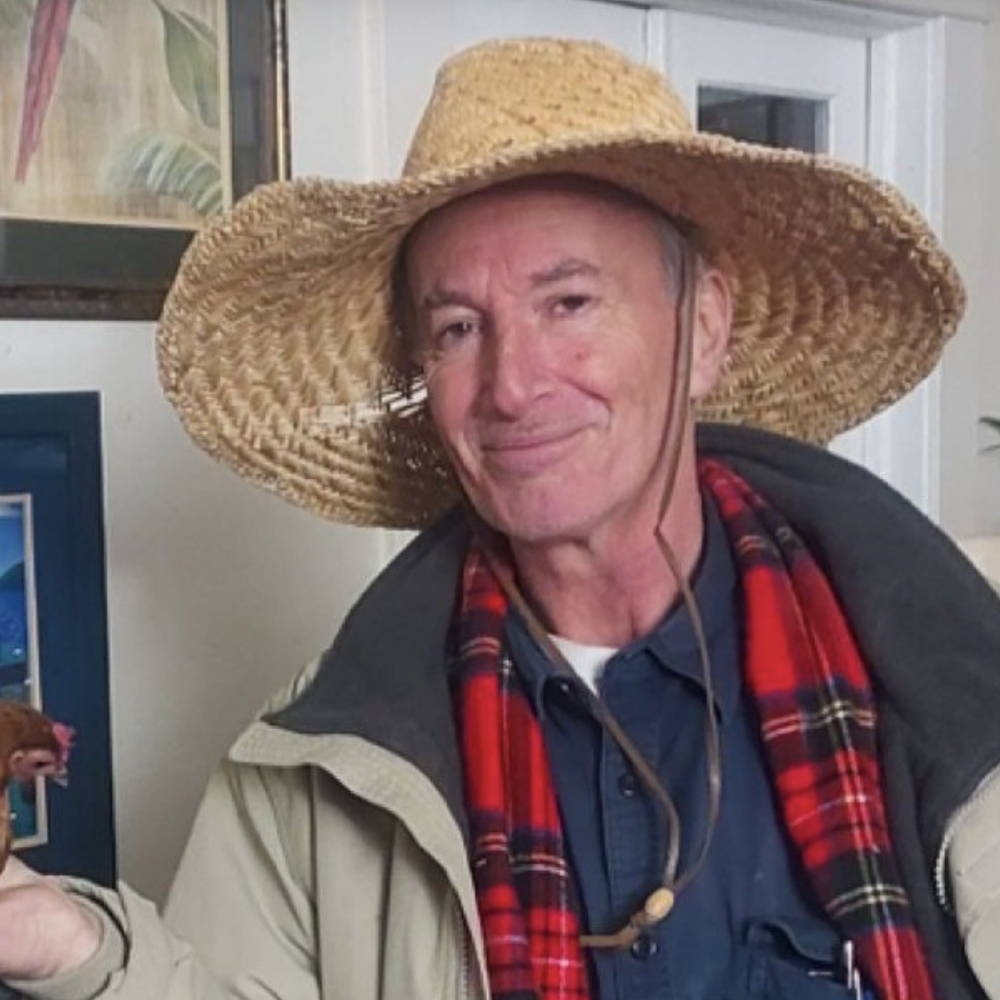 Photo of a man wearing alarge hat and a red checked shirt