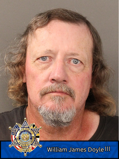 Booking photo of a man with a mustache and beard and a sheriff's badge