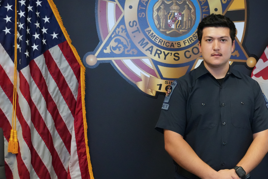 Cadet in uniform standing next to the U.S. Flag